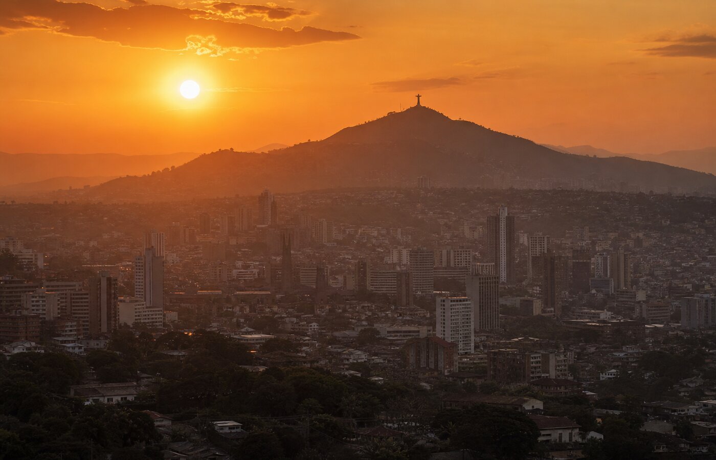 Vista urbana de Cali al atardecer con el Cristo Rey en el horizonte